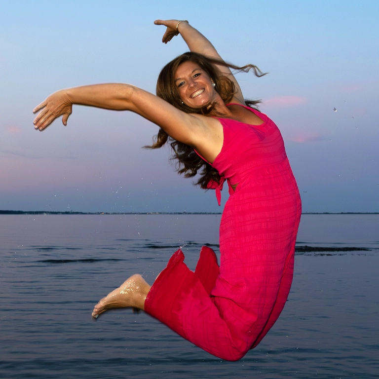 Woman and her family jumping joyfully above the ocean during a family photography session by Fox Red Foto in Lewes, Delaware.